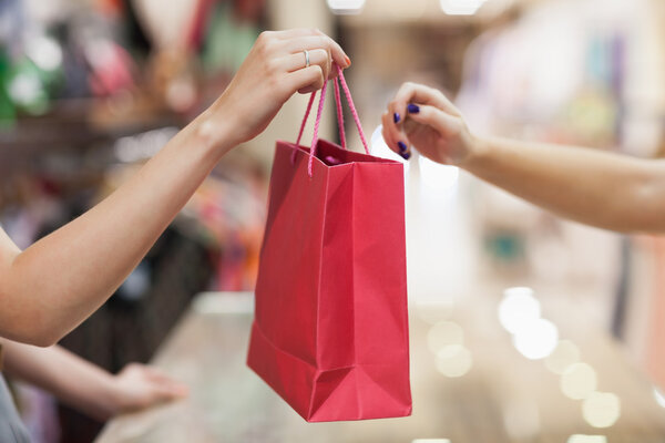 Woman handing over shopping bag — Stock Photo, Image