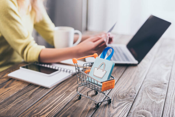 Selective Focus Small Shopping Bag Shopping Trolley Woman Using Laptop — Stock Photo, Image